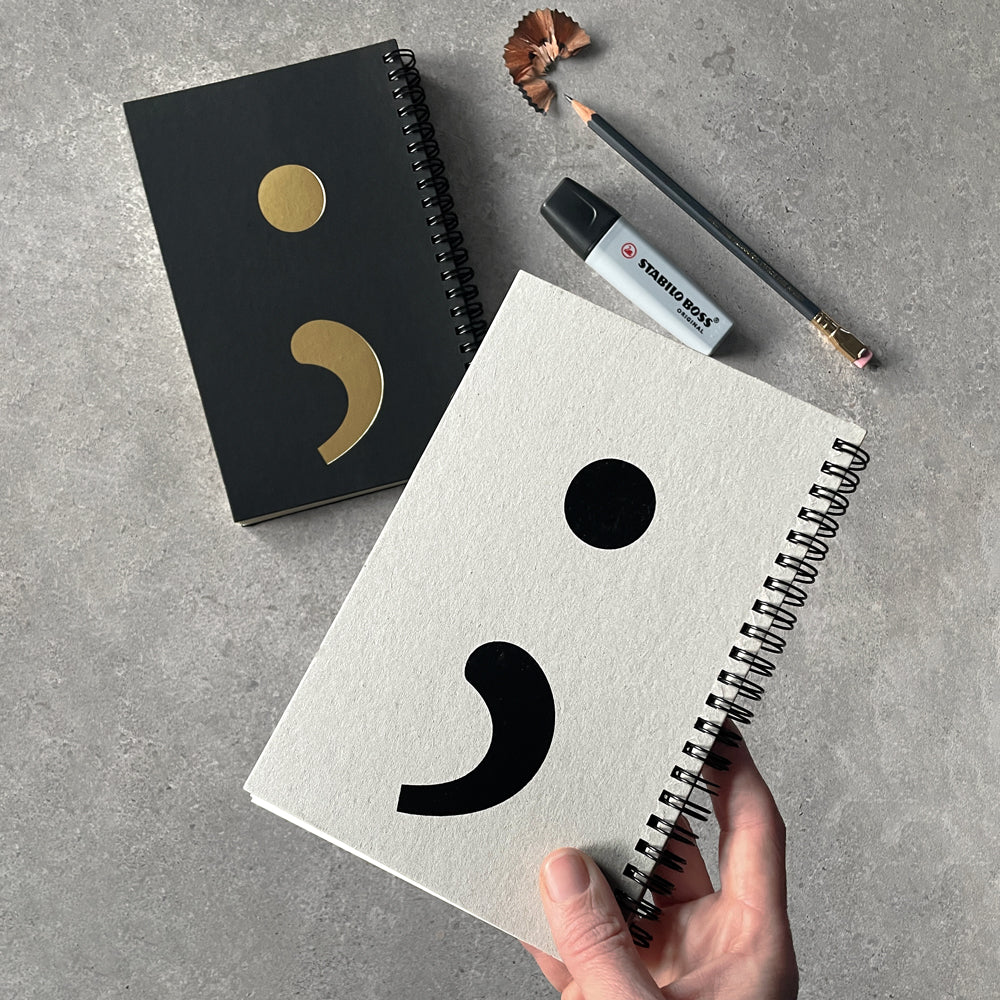 KaRiniTi - A two-way spiral notebook, so you can write from right to left or left to right.  Hardcover in Gray/Black  A Semicolon icon (;) on one side of the cover,  and a colon icon (:) on the other side of the cover.   ▲ Size 13 cm -19 cm  ▲ 80 pages | 40 cream lined paper | 40 cream dotted grid paper   