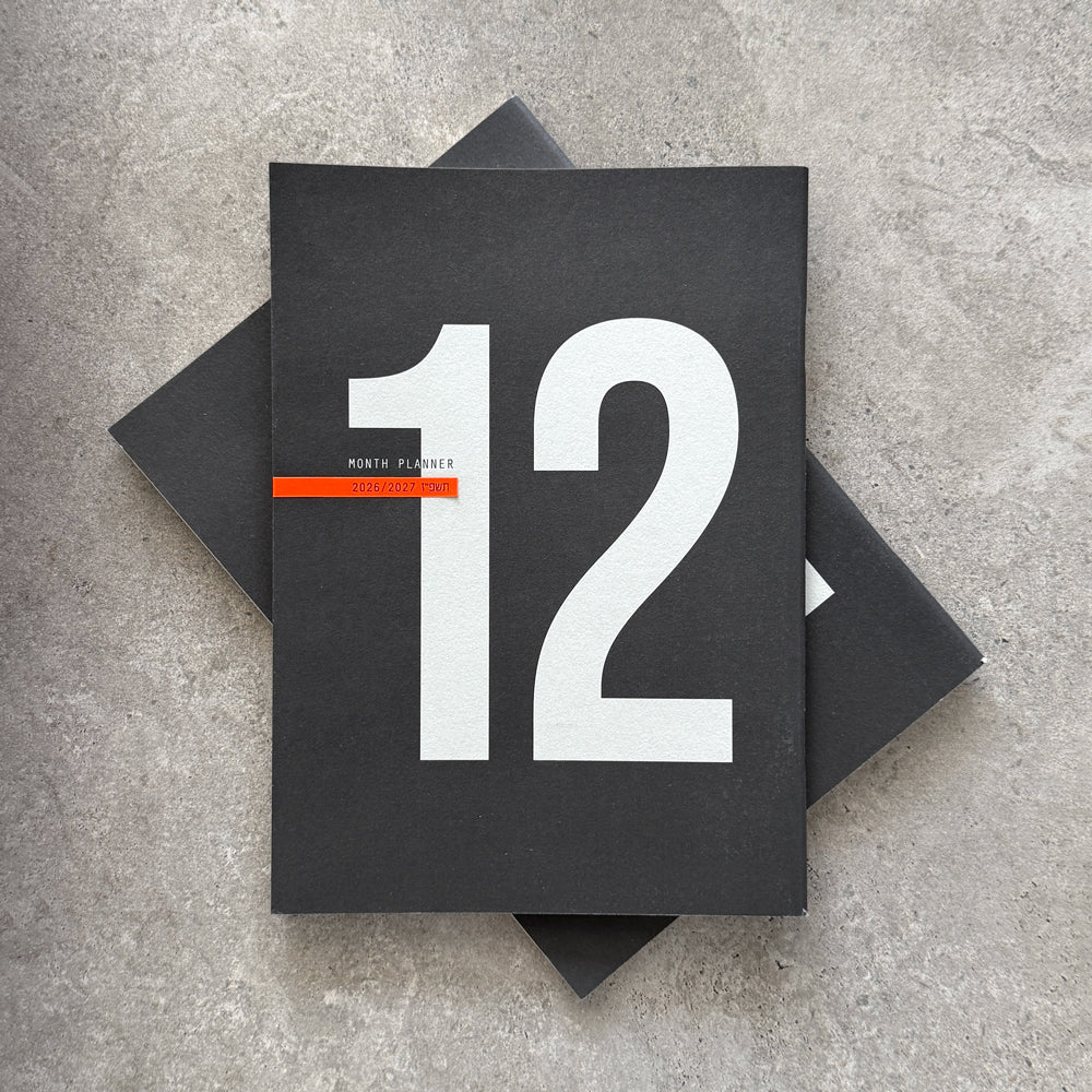 Two black 12-Month Planners stacked, the top one showing a large 12 and an orange stripe