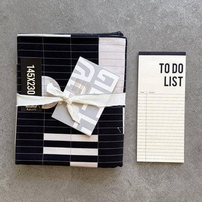 Black KaRiniTi tablecloth folded and tied with a ribbon, beside a To Do List notepad and a Shana Tova greeting card
