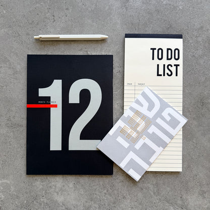 12-Month Planner with a large 12 on a black cover, a To Do List notepad, white gel pen and a Shana Tova greeting card