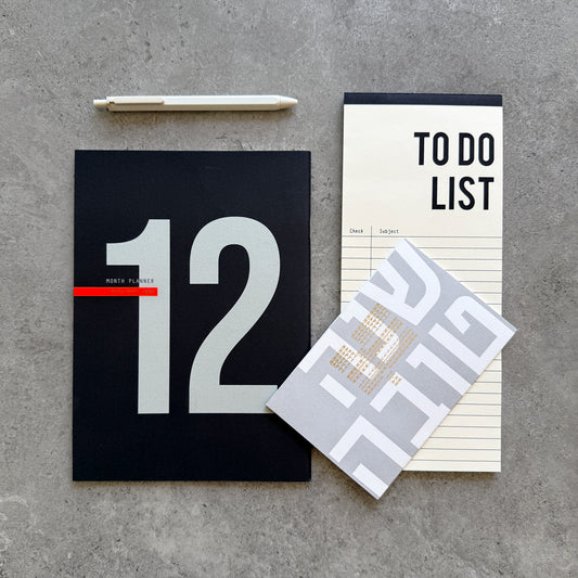 12-Month Planner with a large 12 on a black cover, a To Do List notepad, white gel pen and a Shana Tova greeting card