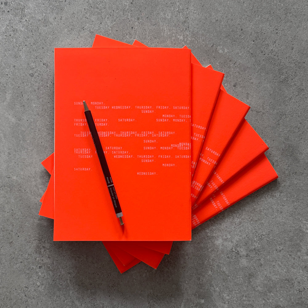 Neon orange notebook cover with delicate white weekday typography — KaRiniTi