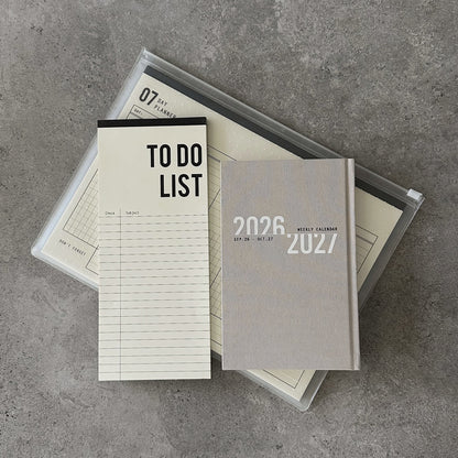 KaRiniTi Super Efficiency 2026/2027 – grey weekly calendar and To Do List atop transparent zip case with 07-day planner inside
