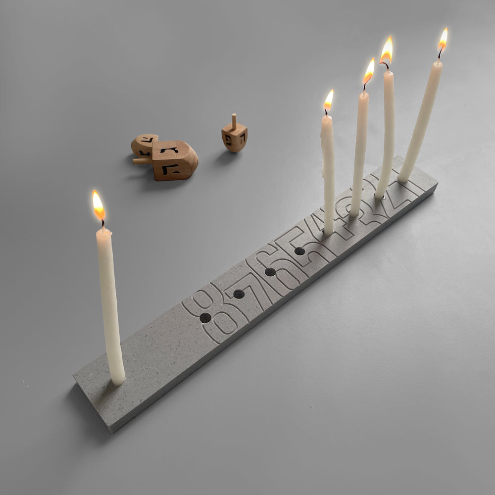 Hanukkah Menorah   The minimalistic design of the classic menora, making it super easy to count the candles.  33 cm x 4.5 cm x 1 cm  Corian DuPont  Color: Stone  ---  * Candle wax easily cleaned with hot water  * Packed in a cardboard box  * The hue and color may vary slightly from item to item